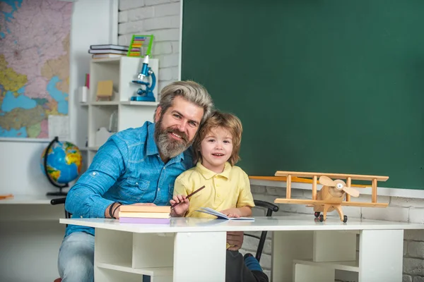 Grundschullehrer. Heimschule für Schüler. Individueller Unterricht. Grundschulklassenzimmer. Lustiges kleines Kind mit Vater hat Spaß auf Tafel Hintergrund. — Stockfoto