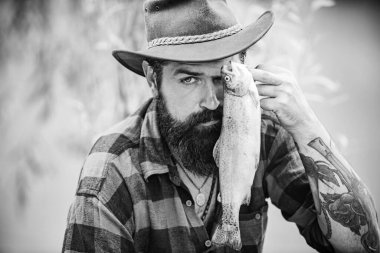 Sakallı adam balık yakalıyor. Başarılı bir yakalayış. Büyük balık avı. Hafta sonları balık tutmak içindir. İyi balık avları. Suyun yanında mutlu bir balıkçı. Yakışıklı adam dinleniyor..