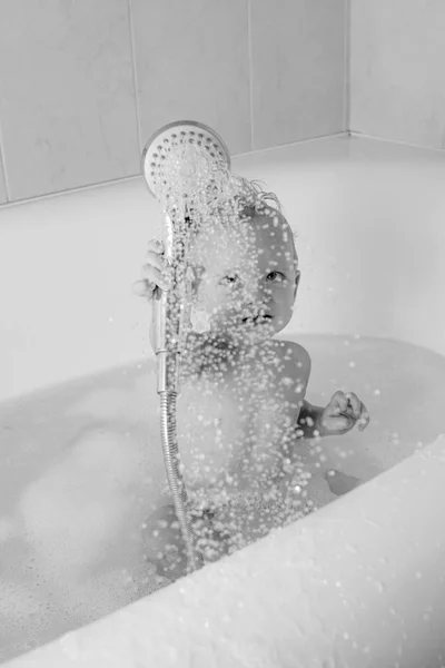 Lindo bebé feliz riendo en albornoz suave después del baño jugando en la habitación de los niños. Agradable niño jugando en el tubo de baño. Bebé baño juguetes . — Foto de Stock