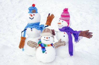 Mutlu kardan adam çifti ve Noel hediyeli kardan adam kışın Noel manzarasında ayakta duruyor. Mutlu Noeller ve mutlu yıllar..