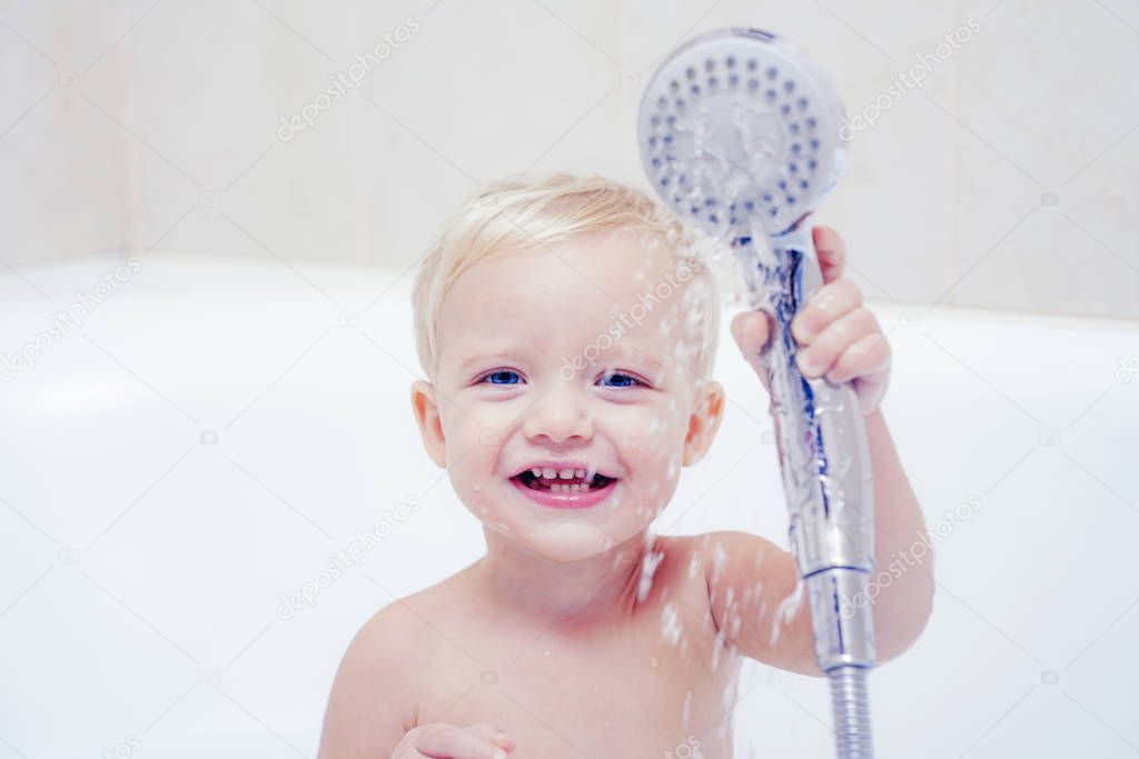 Cute baby is washing her hair in bath. Concept for healthcare and daily routine. Baby with a towel after taking a bath. Kid bath.