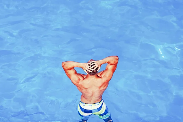 Um tipo sexy em água azul na praia. Modelo masculino sexy em roupa de banho. Jovem feliz se divertindo na praia no dia ensolarado. Feliz estilo de vida no mar. Organismo sanitário . — Fotografia de Stock