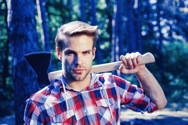 Ciddi yüzdeki oduncu omzunda balta taşıyor..