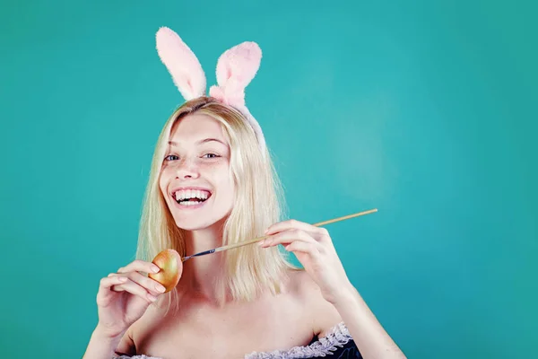 Linda loira sensual. Jovem feliz pintando ovos em um fundo verde. Menina loira vestindo orelhas de coelho e tendo ovos de Páscoa. Coelho coelho. — Fotografia de Stock