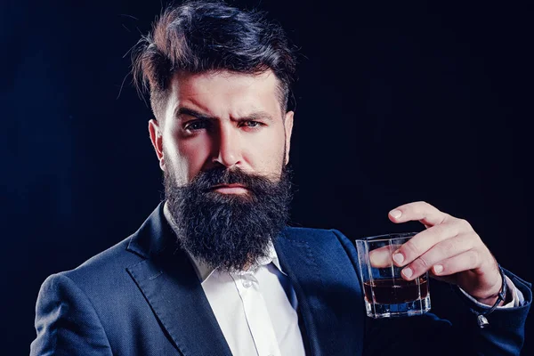 Hipster z brodą i wąsami w garniturze pije alkohol po dniu pracy. Stary tradycyjny napój whisky - napój dla panów. Elegancka whisky. — Zdjęcie stockowe