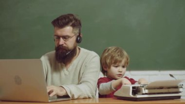 Masada eski daktilo ve dizüstü bilgisayar var. Teknoloji gelişimi kavramı. Baba ve oğul. Yaşlılar ve gençler.