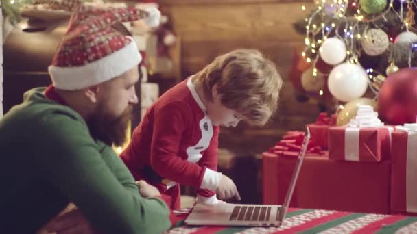 Father and son having fun on Christmas. Cute little son with father with notebook. Christmas family. Happy father and son in Santa hat with present have a Christmas. — Stock Video