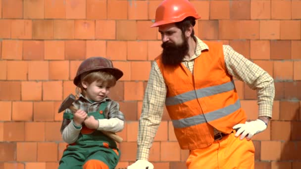 Père et petit fils avec foret perforant la planche de bois à l'atelier. Père et Fils construisent ensemble une maison. Le petit et son père construisent la maison ensemble. Bâtiment père et fils . — Video