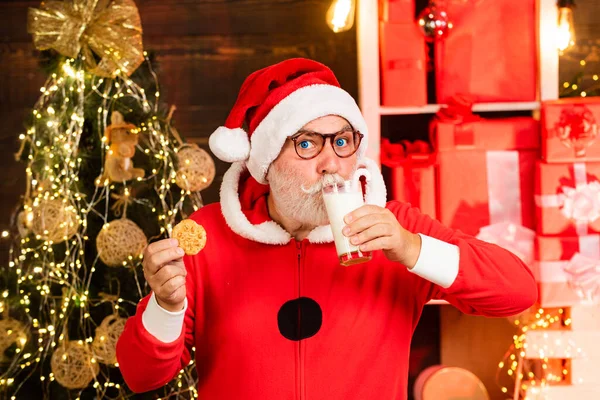 Dia de Acção de Graças e Natal. Feliz Ano Novo. Papai Noel com barba e bigode. O Pai Natal a escolher bolachas. Diversão do Pai Natal. Papai Noel leva um biscoito na véspera de Natal como um presente de agradecimento para presentes . — Fotografia de Stock