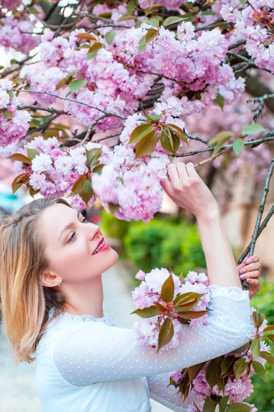 Vacker kvinna med blommande Sakura träd och solig dag. Daisy blomma, blommande tusensköna blommor på ängen. — Stockfoto