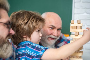 Büyükbabam torununa Jenga oynamayı öğretiyor. Büyükbaba ve oğul birlikte eğleniyorlar. Erkek Aile Jenga Oynuyor.