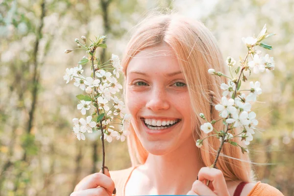 幸せな女性の肖像画を閉じます。白い花と春の境界線の背景。枝先の女性繊細な春の花. — ストック写真