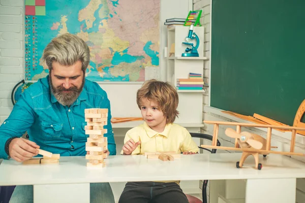 Vater und Sohn spielen zusammen. Schüler der Grundschule lernen drinnen. Bildung für Schüler. — Stockfoto