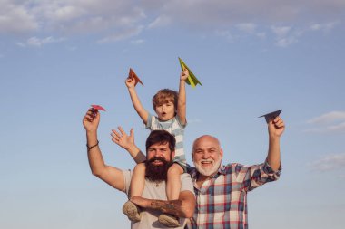 Mutlu gülümseyen çocuk, baba kameraya bakıyor. Mutlu bir aile. Kağıt uçakla seyahat eden çocuk pilot. Üretim kavramı.