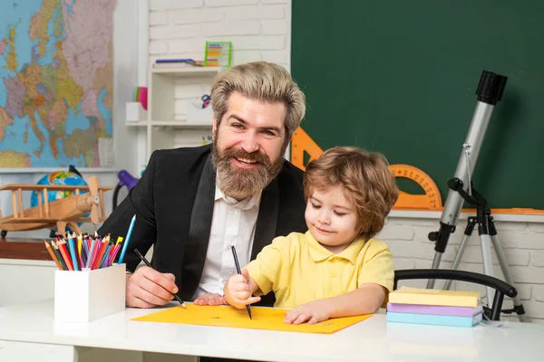 Cute little preschool kid boy with teacher study in a classroom. Teacher and pupil in classroom. — Stock Photo, Image