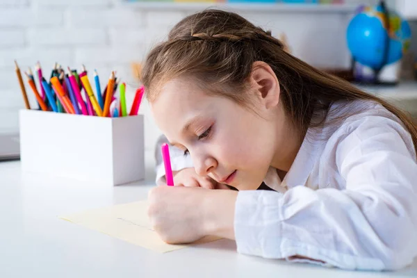 Šťastná veselá holčička kreslí. Koncept tvořivosti. Roztomilé dětské kreslení pomocí plstěného hrotu pera při sezení u stolu. — Stock fotografie