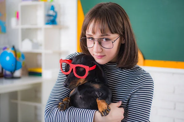 Funny puppy in glasses. Teenager girl with puppi. Happy smiling teenager girl go back to school. Funny education. Smart and clever dog with glasses.