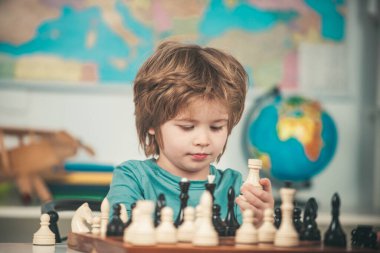 Anaokulu ya da okul çocuğu, düşünen çocuk. Çocuk odada satranç oynuyor. Satrançlı küçük çocuk.