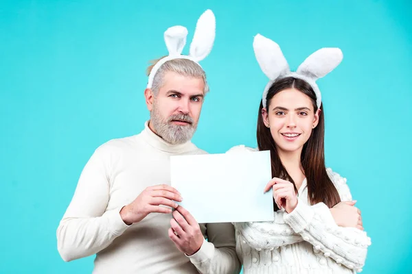 Påskpar som håller blank vit tavla för din text. Porträtt av glada påsk par. — Stockfoto