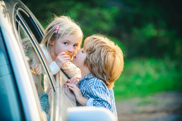 Dá um beijo quente. O rapazinho despede-se da menina. Conceito de despedida. A menina diz adeus ao namorado que navega por muito tempo. Engraçado casal dizendo adeus antes de viajar de carro . — Fotografia de Stock