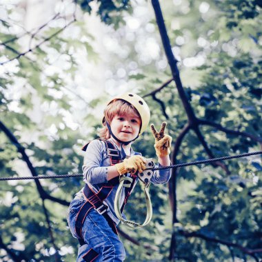 Bir ağaç evde veya bir ip parkta güvenlik ekipmanları tırmanma Sevimli çocuk halat tırmanıyor. Mutlu küçük çocuk açık bir ip oyun alanında tırmanma. Çocuk bahçesi.