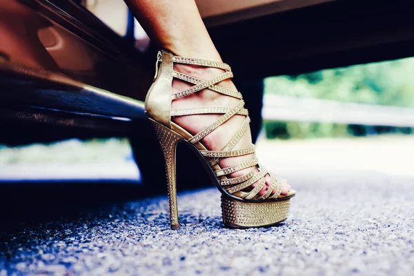 Womans legs in high heels. Luxury urban background. The woman is wearing shoes on high heels. Close up of woman legs. Woman legs in high heel golden shoes heels.