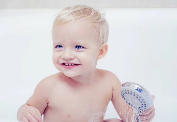 Lächelndes Kind im Badezimmer mit Spielzeugente. lächelnder kleiner Junge, der zu Hause unter der Dusche badet. Kleines Kind badet in Seifenlauge. — Stockfoto