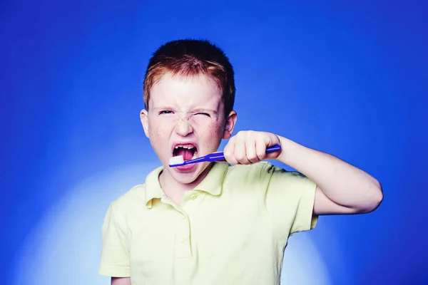 Adorable little boy holding toothbrush and smiling at camera. Mockup, free spase. Cute funny boy with a toothbrush. Dental concept - smiling teenage girl in blank white shirt brushing her teeth. — Stock Photo, Image