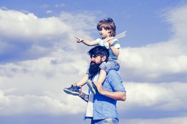 Baba ve oğul. Çocuk babasının omuzlarında oturuyor. Nesil. Mutlu çocuk kağıt uçak ile oynuyor.