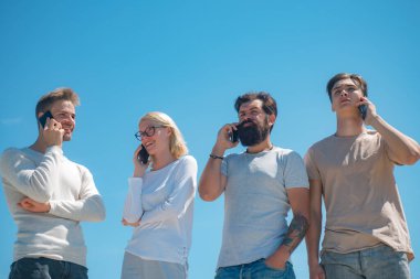 Arkadaşlar randevu alır. Mavi arka plandaki genç ekip izole edildi. Gözlüklü tatlı sarışın telefonda konuşuyor. Gökyüzü arka planı. Telefonu kullan..