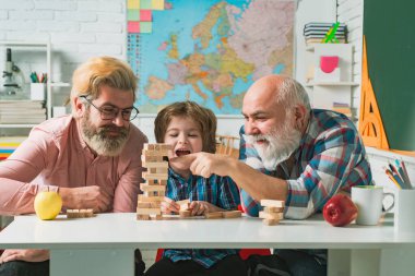 Büyükbaba ve oğul hafta sonunu birlikte geçiriyorlar. Mutlu adamlar aileyi sever. Erkek Aile Jenga Oynuyor.
