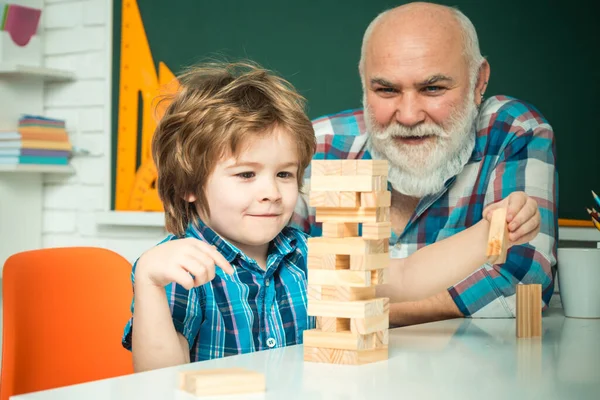 Happiness family life style concept. Three different generations ages: grandfather and child son together. Cute happy boy playing Jenga with his grandfather — ストック写真