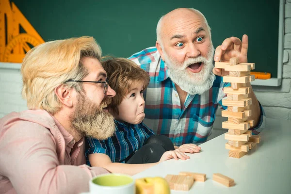 Ridendo nonno con figlio e nipote rilassante trascorrere il fine settimana a casa. Famiglia felice uomo divertirsi insieme e giocare a Jenga . — Foto Stock