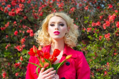 Çiçekli kırmızı elbiseli güzel kız. Çiçekli laleler, bahar çiçekli arka planda..