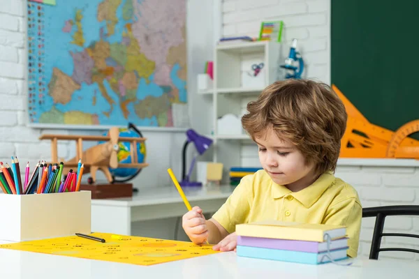 Wracać do szkoły. Szczęśliwy uśmiechnięty uczeń rysujący przy biurku. Portret ucznia w klasie. Indywidualne nauczanie. Korepetycje indywidualne. — Zdjęcie stockowe