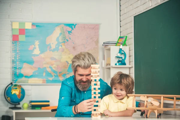 Šťastný otec a syn u stolu, hrají deskové hry. Předškolní výchova. Podporující žáky ve škole. Otec a syn spolu vychovávají. — Stock fotografie