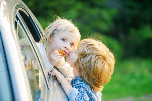 Dois miúdos a despedirem-se antes de viajar de carro. Menino dá beijo para a menina bonito. Adeus antes de viajar de carro . — Fotografia de Stock