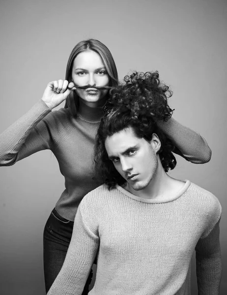 Beautiful girl playing with her boyfriend hair. Different types of hair concept. Happy couple in love studio photo. Handsome man with long wavy hair and his cute girlfriend.