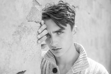 Ciddi bir yüz. Gri arka plandaki yakışıklı genç adam kameraya bakıyor..