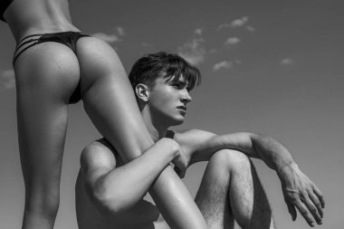 Blue Sky arka planında seksi aşıklar var. Kadınların bacakları ve kalçaları formda. Tutkulu kız arkadaşı olan genç bir adam. Lüks bikinili seksi kız..