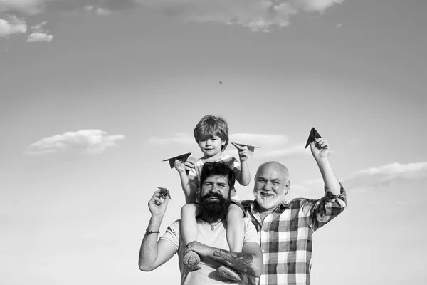 Boldog nagyapa és unokája játékpapír repülőgép felett kék ég és felhők háttér. Boldog férfiak szeretik a családot. Apa és fia együtt pihennek.. — Stock Fotó