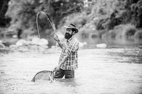 Szakállas halász a vízben. Fiatalember horgászik. Sikeres legyező horgászat. Fisher férfi hobbija. Férfi horgászbottal és hálóval. Csaló mester. Horgászni. Igazi boldogság. Aktív napsütéses nap. — Stock Fotó