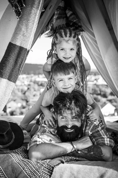 Genç yakışıklı baba boş zamanlarını çocuklarla geçiriyor. Çocuklar başlarını babalarıyla dikey bir sıraya koyarlar. Çatıdaki küçük piramit evi aileyle eğlenmek için.. — Stok fotoğraf