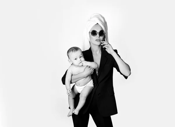 Lovely young working mother and her baby. Work life balance concept. Working mother working at home. Business woman talking on her cellphone with towel on head and in glasses. — Stock Photo, Image
