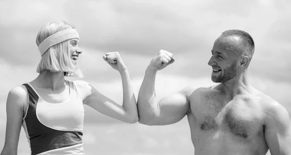 Beautiful smiling girl compares muscles with her strong handsome boyfriend and have fun. Shirtless muscular sporty man and skin woman do sport exercises at sky background. — 스톡 사진