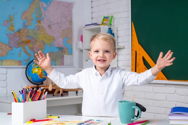 Proces edukacyjny. Zabawny mały uczeń zadowolony z doskonałego wyniku. Uczeń uczy się liter i cyfr. Badanie domowe. — Zdjęcie stockowe