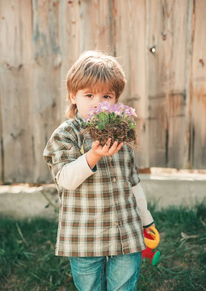 Ημέρα της Γης. Το αγόρι με τις μπότες παίζει στο ανοιξιάτικο γήπεδο. Κηπουρική δραστηριότητα με μικρό παιδί. Το παιδί περνάει χρόνο στο περιβόλι.. — Φωτογραφία Αρχείου
