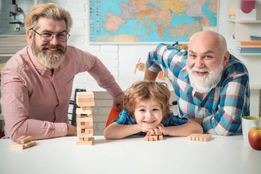 Mutlu erkek ailesi birlikte eğleniyor. Büyükbaba, oğluyla torununu evde masa oyunu oynarken izliyor..