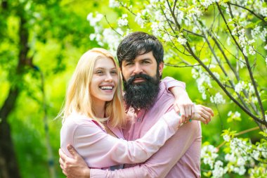 Yeşil bahar sonbahar çifti. Şefkatli aşk duyguları. Sevgi dolu bir adam ve kadın bahar çiçekli bir parkta yürüyorlar..