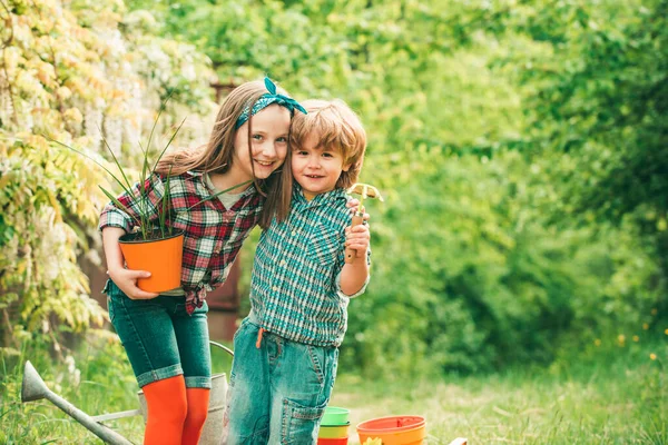 Tavaszi kertészkedés. Kisgyermek fiú és lány kertészkedés és szórakozás a tavaszi kertben. — Stock Fotó
